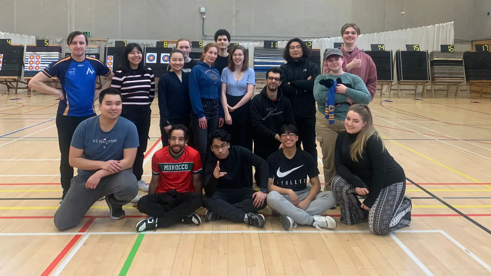 A squad of student archers gathered on the shooting line at an ISAA intervarsity, with numbered target bosses behind them
